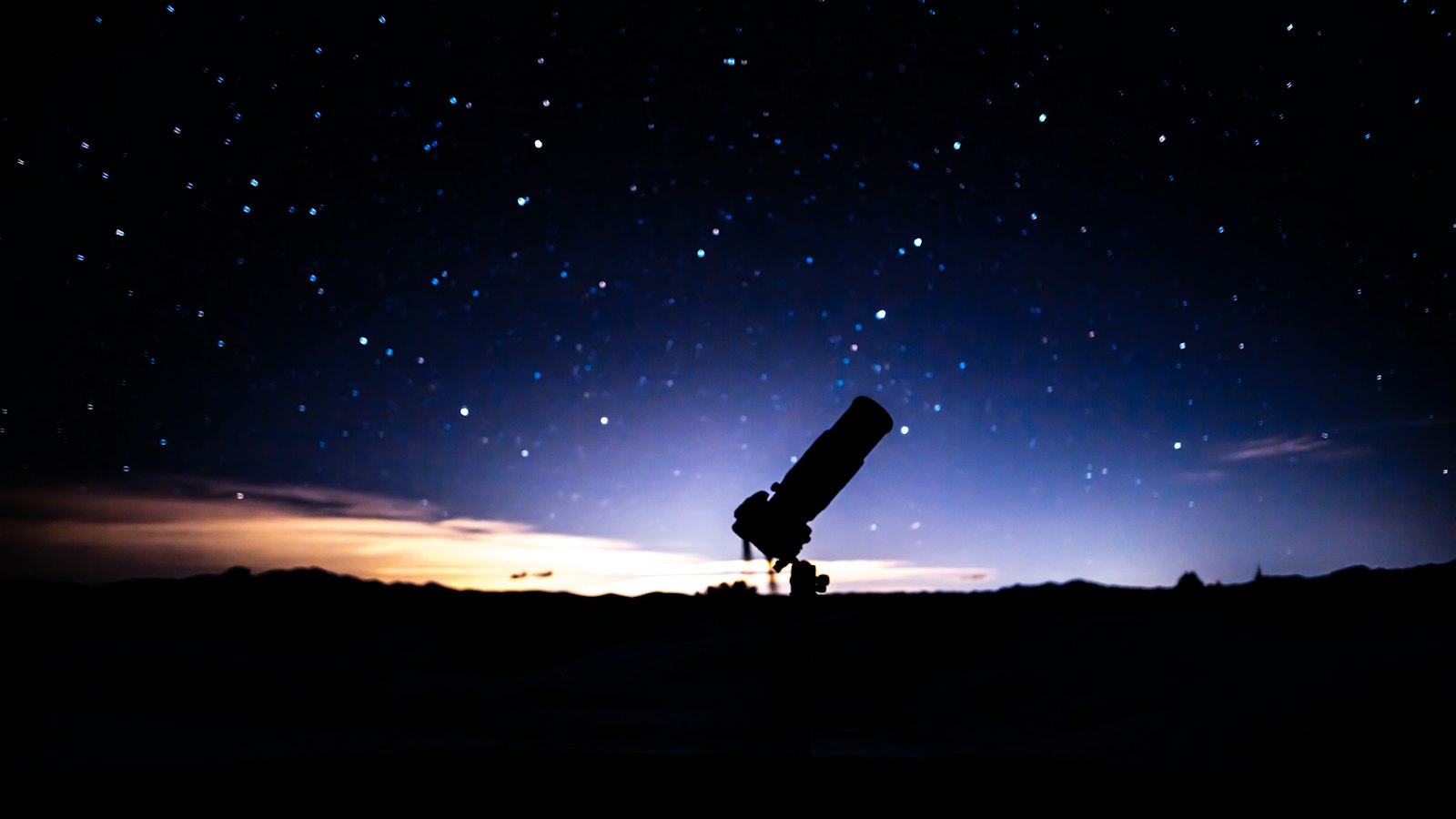 Telescope on a hill under a starry night sky
