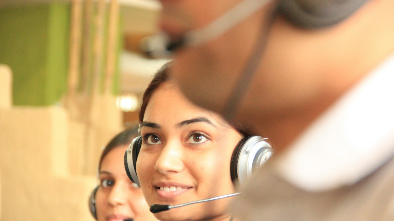 Two women wearing headsets in a bright office